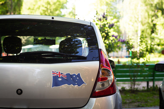 Car with an Australian flag sticker on the back, parked outdoors with greenery in the background.