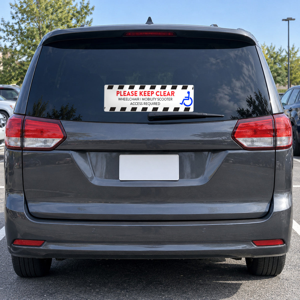 Option 4 white decal with black hazard stripes, a blue wheelchair symbol and red PLEASE KEEP CLEAR, WHEELCHAIR / MOBILITY SCOOTER ACCESS REQUIRED, on the rear window of a charcoal minivan.