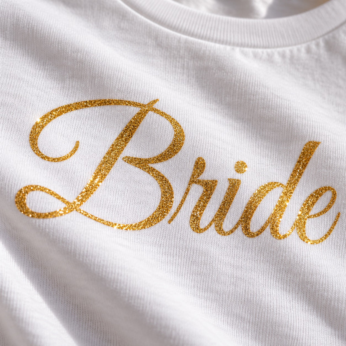 Close-up of gold glitter heat transfer vinyl lettering 'Bride' on cotton