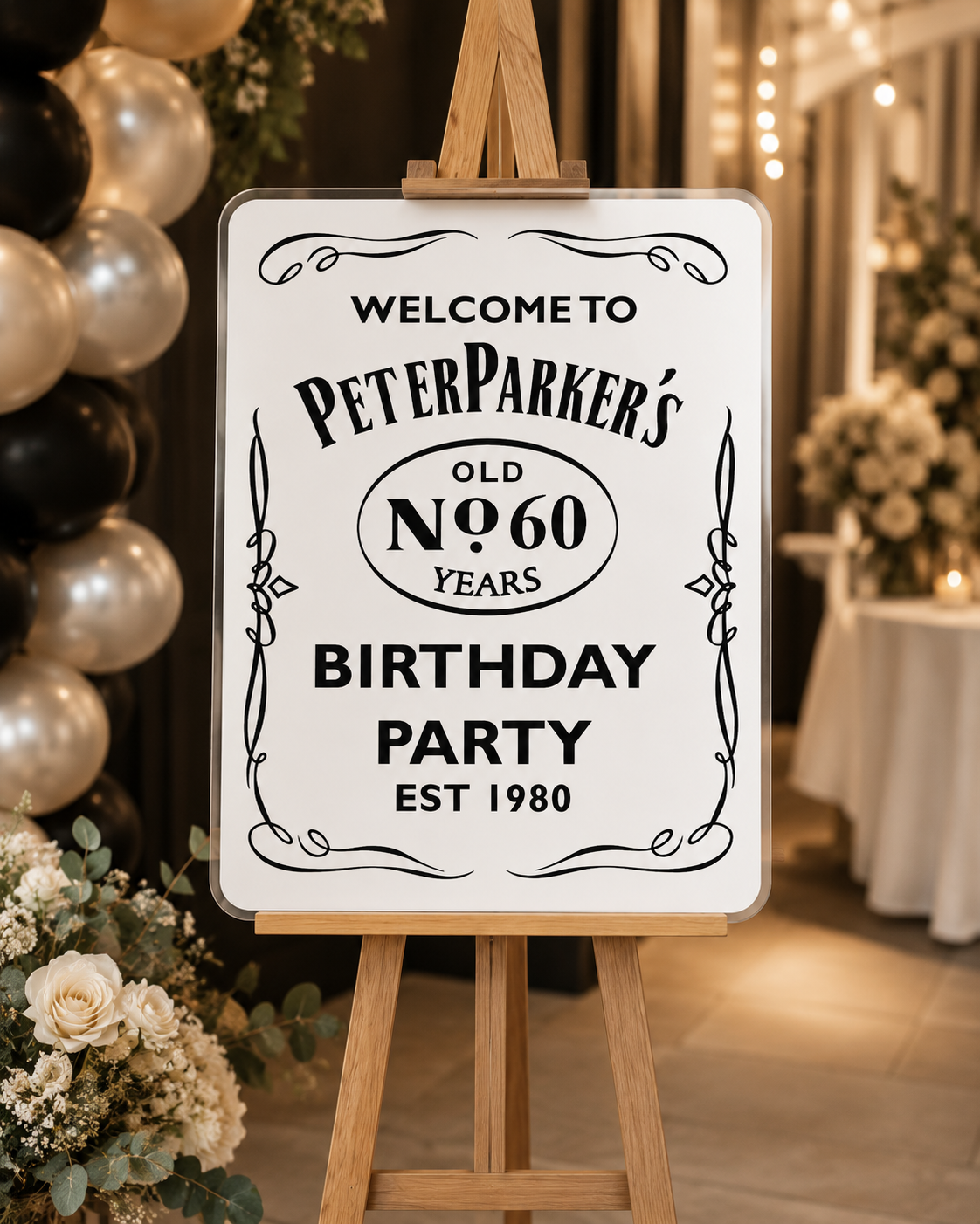 White acrylic birthday welcome sign on a timber easel with black lettering, styled with balloons and florals