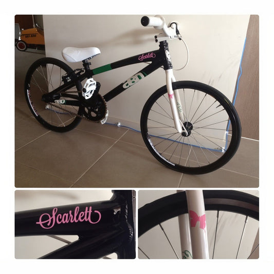 Bike name decal – pink script name Scarlett on a black BMX frame, with a pink bow on the white fork in close-ups