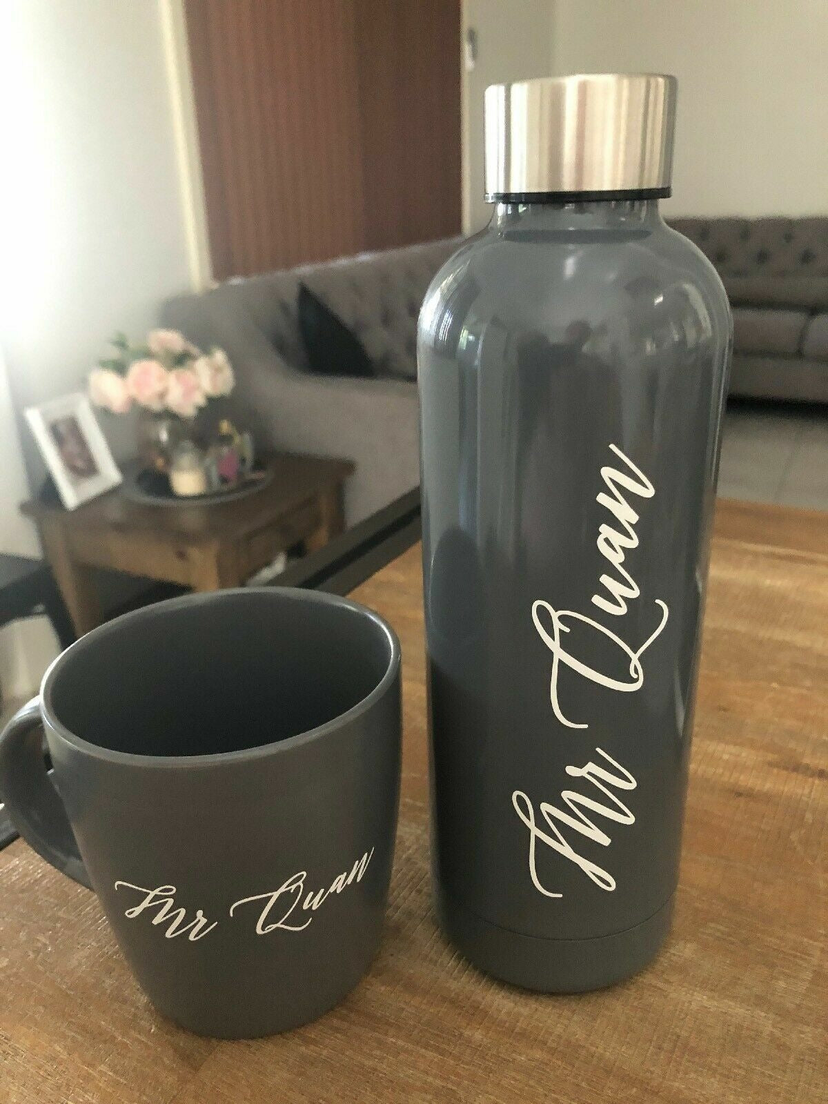 Grey drink bottle and matching mug with a personalised name decal in white script
