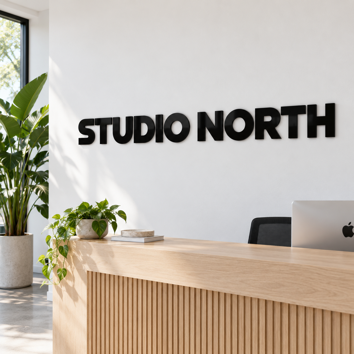 Black gloss 6 mm acrylic letters 'STUDIO NORTH' on a reception wall