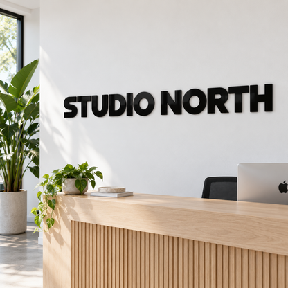 Black gloss 6 mm acrylic letters 'STUDIO NORTH' on a reception wall