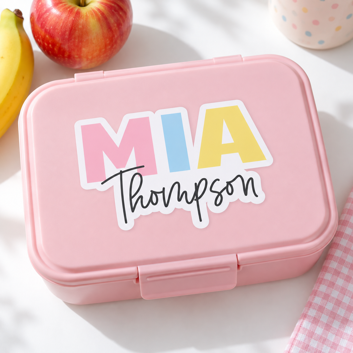 Pastel rainbow first and last name sticker on a pink kids' lunchbox lid