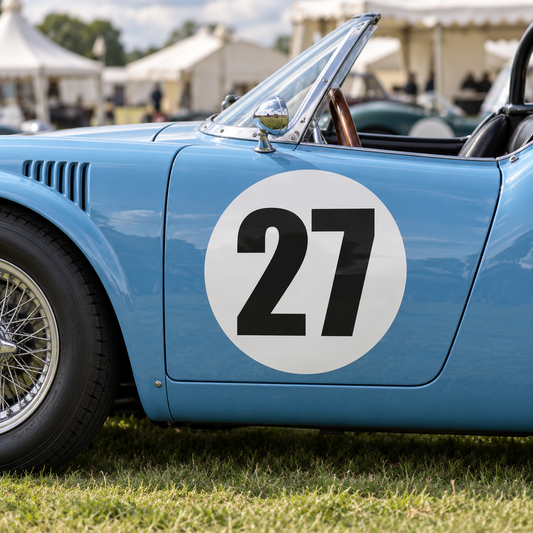 White round race number background panel on a vintage race car door, shown with an example number 27, numbers not included