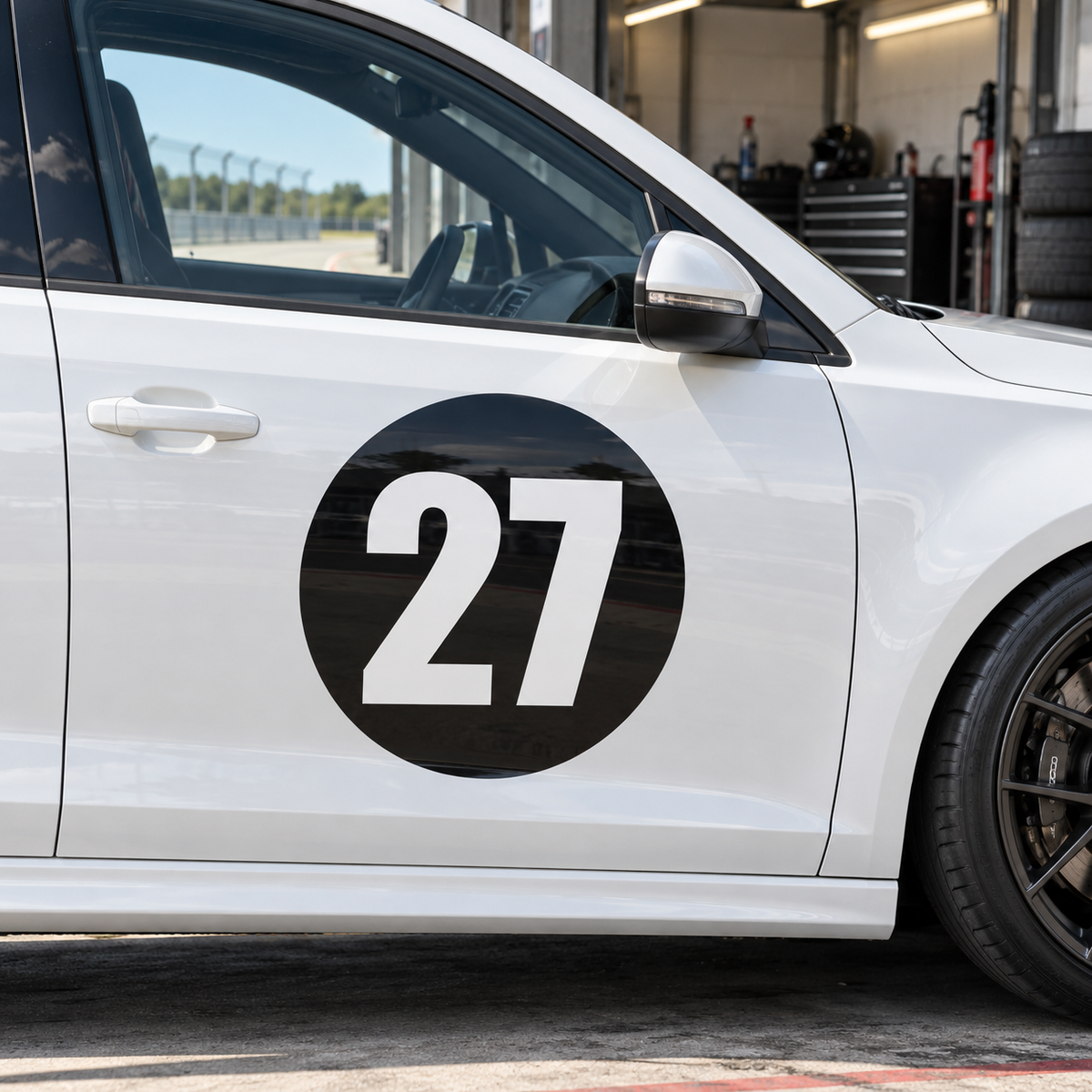 Black round race number background panel on a white car door, shown with an example number 27, numbers not included