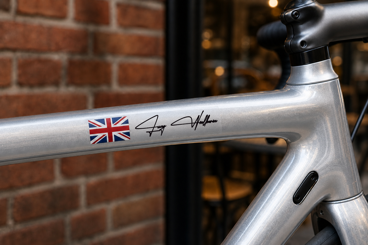 Custom flag and name sticker in signature script with black lettering on a silver bicycle top tube, with Union Jack flag