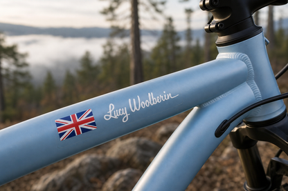 Custom flag and name sticker in calligraphy script with white lettering on a light blue bicycle frame, with Union Jack flag