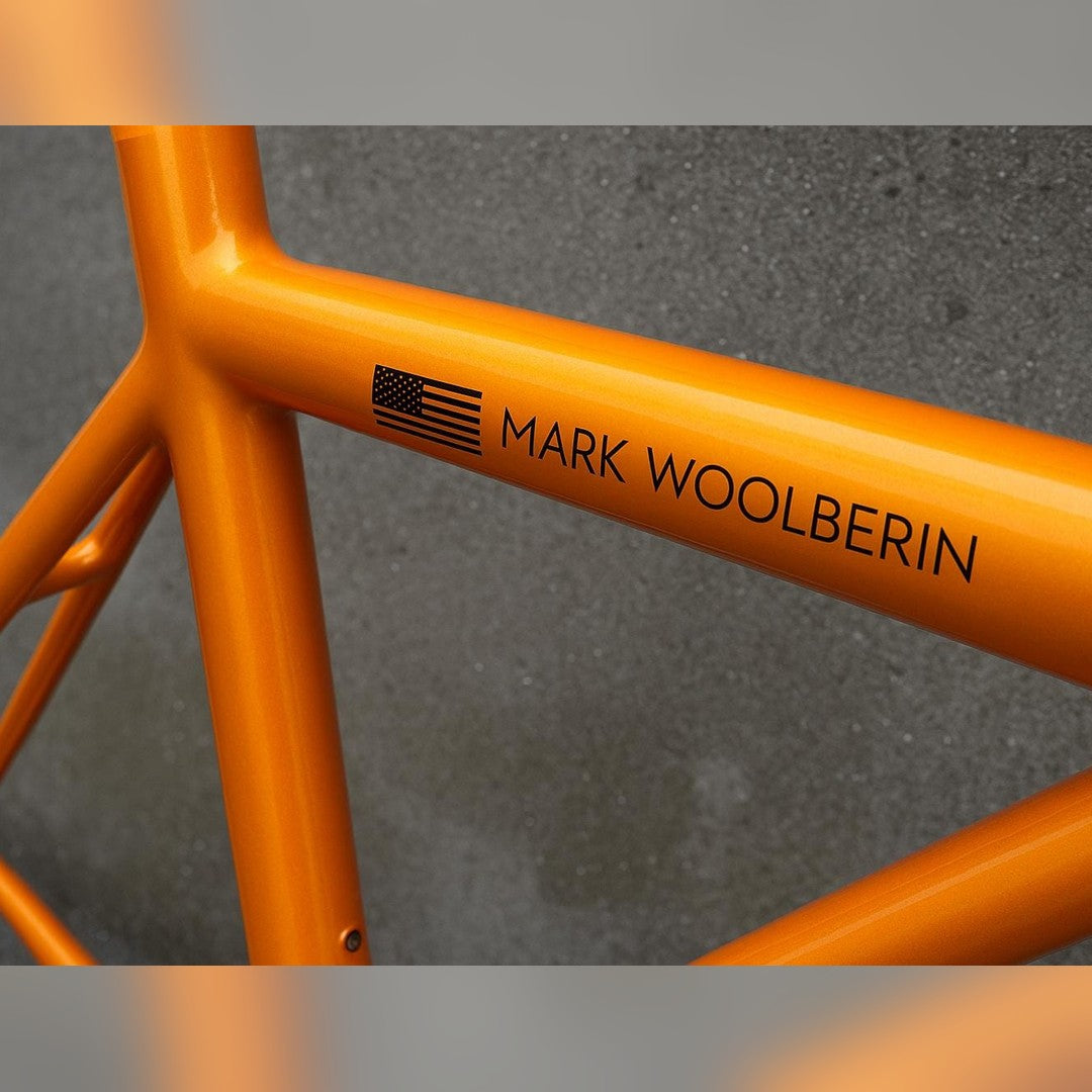 American flag sticker – black flag and name lettering on the top tube of an orange bike frame