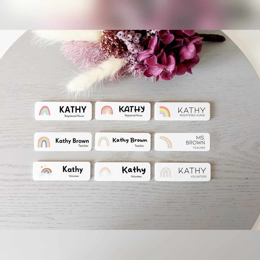 Rainbow name badge options chart – nine white badges with small rainbow icons, names and job titles beside dried flowers