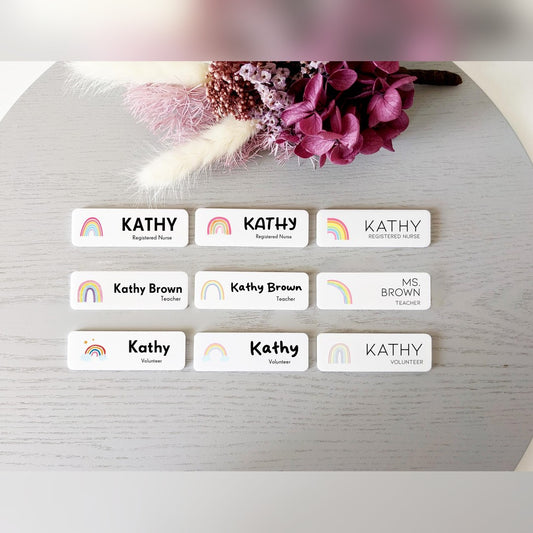 Rainbow name badge options chart – nine white badges with small rainbow icons, names and job titles beside dried flowers